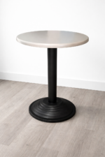 Round café table with light-colored top and black pedestal base for restaurant use